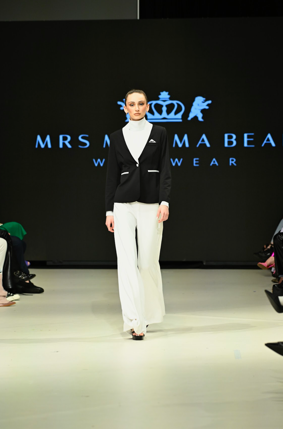 Model walking the runway in a black and white Enza Marie set featuring Mrs. Momma Bear branding at Vancouver Fashion Week.