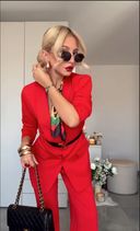 Woman in a red outfit with sunglasses and a black handbag in an indoor setting