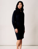 Model wearing a sleek black Blossom Blouse Bodysuit with long sleeves and fitted bottom.