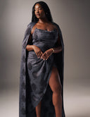Model showcasing the Come Closer dress with a ruched neckline and high split-leg, featuring an optional statement cape.