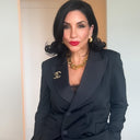 Woman wearing a black blazer with a visible brand logo, standing indoors.