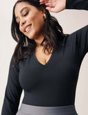 Model showcasing the Luxe Long Sleeve Bodysuit in black with flattering V-neck design, perfect for versatile styling.