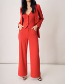 Stylish woman in a tailored red suit featuring a fitted blazer and wide-leg pants, exuding modern elegance.
