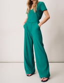 Model wearing a stylish teal Peony Pant with a high-rise waistband and wide legs, featuring functional pockets.