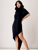 Woman in a black asymmetrical Willow Dress showcasing elegant draping and modern silhouette.