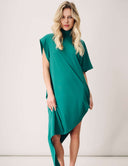Woman wearing an elegant green Willow Dress with an asymmetrical hemline and mock neck, showcasing comfort and style.