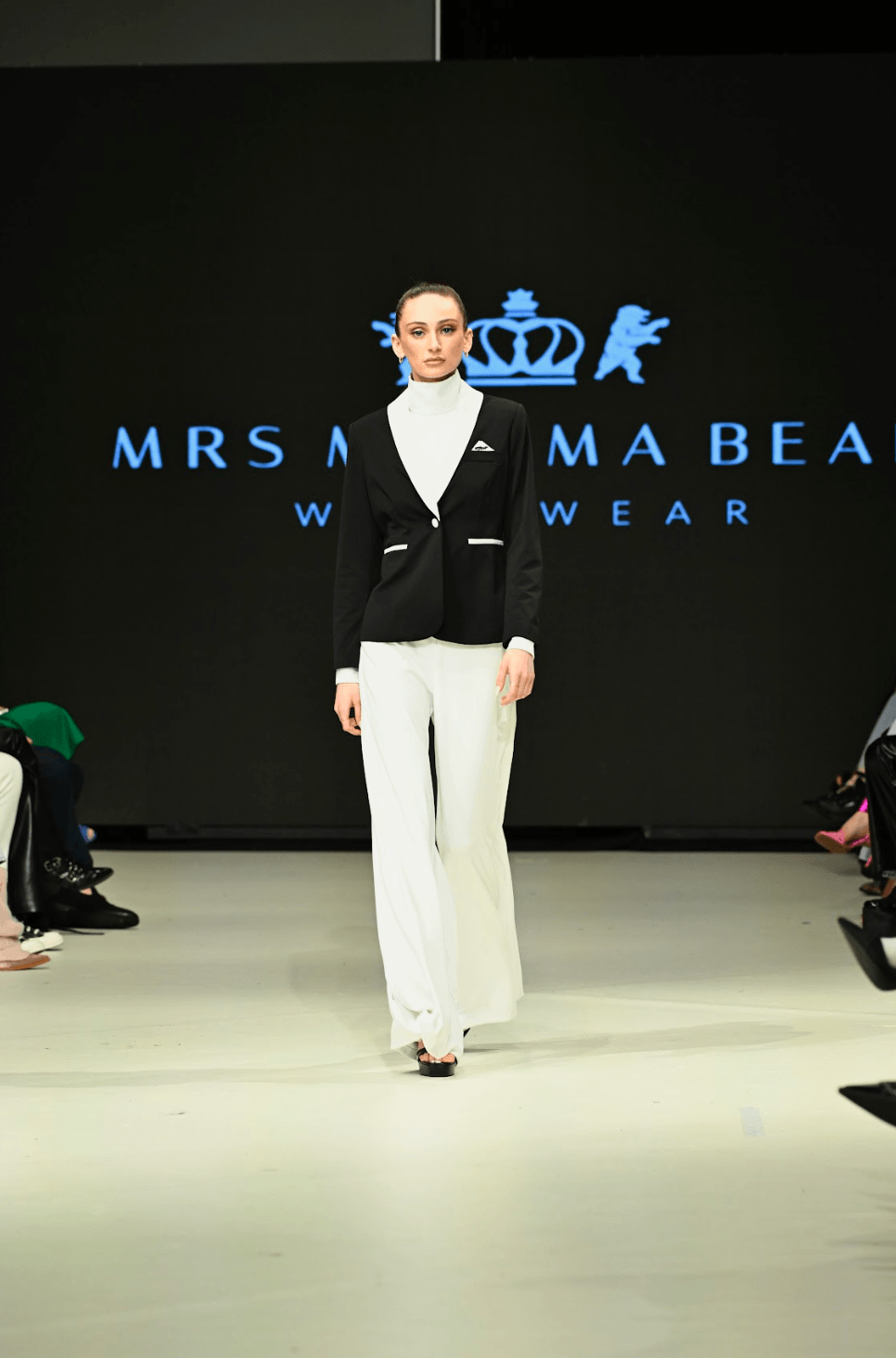 Model walking the runway in a black and white Enza Marie set featuring Mrs. Momma Bear branding at Vancouver Fashion Week.