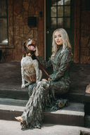 Woman in a stylish green dress sitting with a dog on porch steps, showcasing elegant Texas fashion.