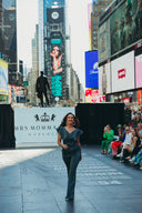 Model walking in Times Square during a fashion event, showcasing stylish denim attire with a vibrant audience.