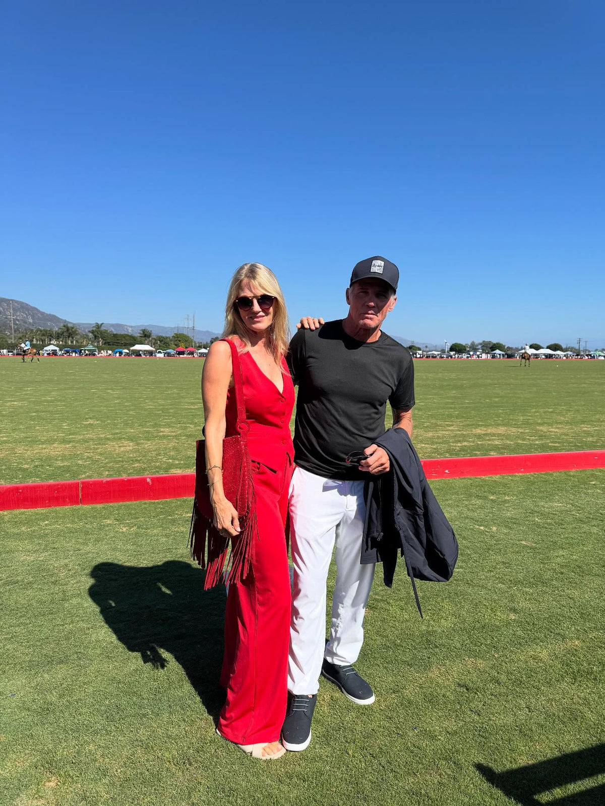 Co-Founder of Lonesome Wind Ranch, Amy Azzaro at a polo event in a red dress with a companion.