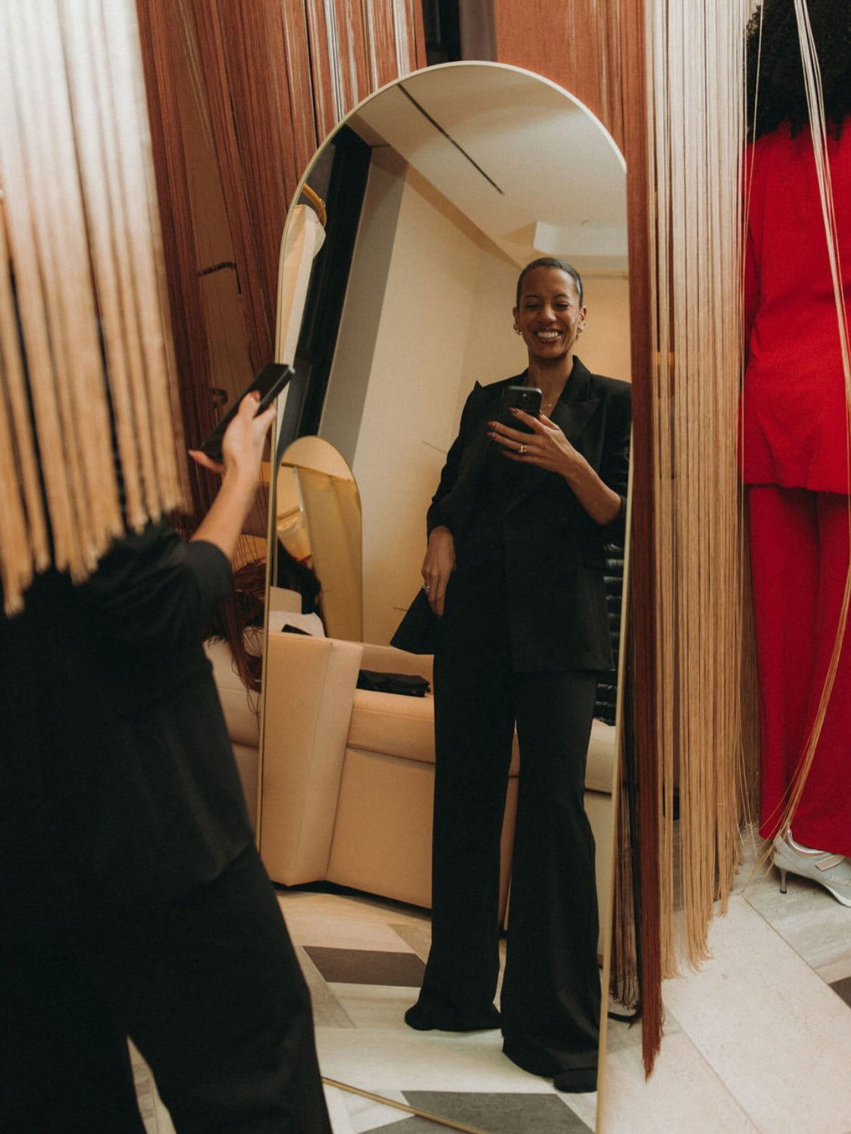 Fashion Designer, Carly Cushnie posing in front of a mirror wearing a stylish black suit.