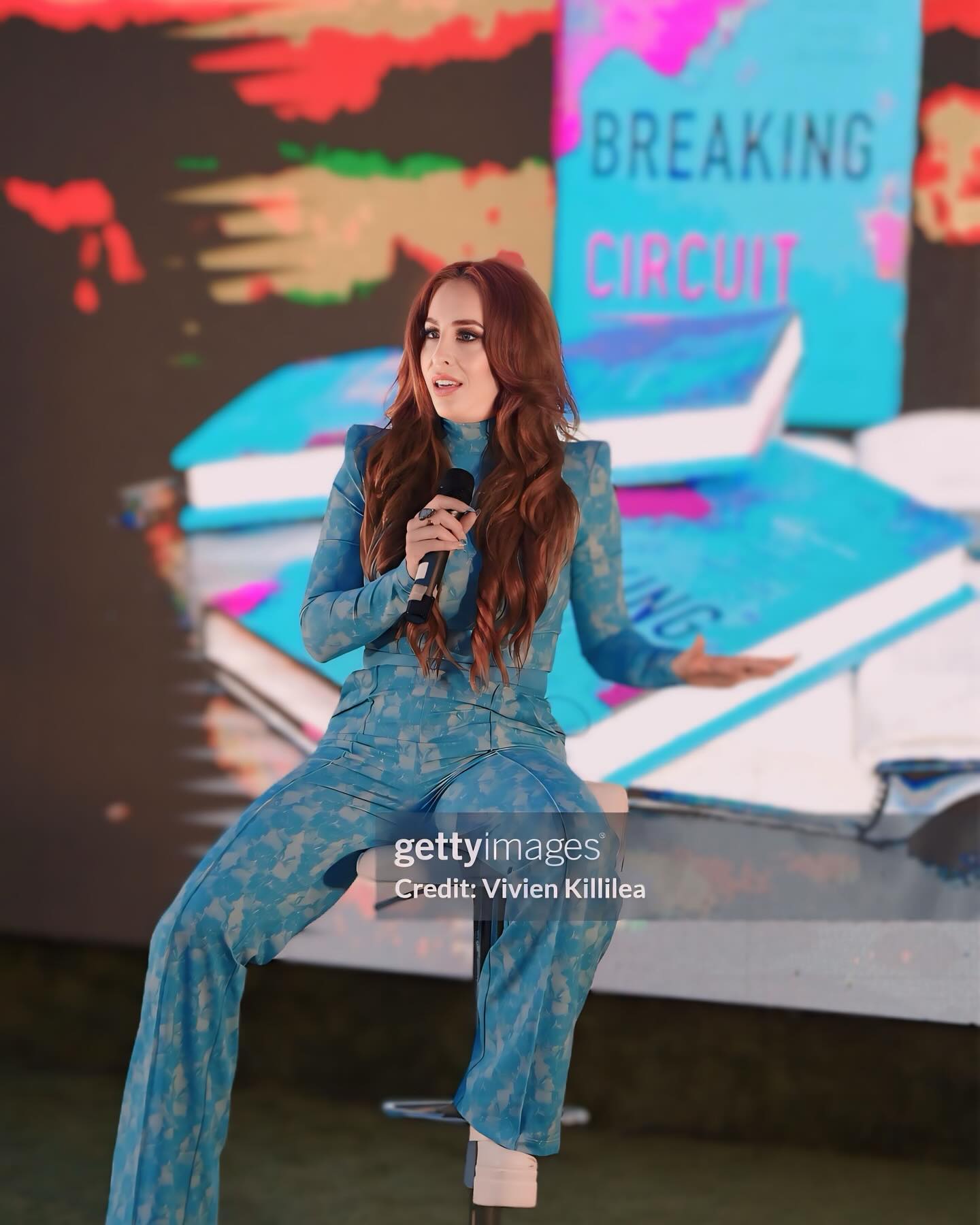 Dr. Samantha Harte sitting on stage, promoting her best-selling book 'Breaking Circuit' during an event.