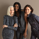 Three women of diverse ages and backgrounds pose together smiling, showcasing elegant and modern clothing.