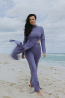 Cut to the Chase Set - Wisteria worn by a model walking on the beach with ocean waves in the background.