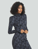 Elegant model showcasing a midi length black dress with a floral pattern and long sleeves against a light background.