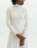 Woman wearing Enza Marie Top, a sleek white mock neck long sleeve top, showcasing minimalist style and elegance.