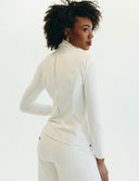 Model showcasing the Enza Marie Top, featuring a sleek mock neck and long bell sleeves in elegant white.