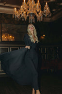 Model showcasing the Promise Me Nothing Set - Obsidian with flowing fabric under a chandelier.