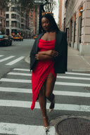 Come Closer dress on a model in a city street, showcasing modern glamour with a high split-leg design.