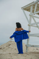 Model wearing a bold blue Dahlia Blazer at the beach, showcasing the elegant design and structured fit.