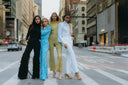 Four models showcasing Fringy Baby, Fellini, Lucky Lady, Meet Me at Noon Set in vibrant outfits on a busy city street.