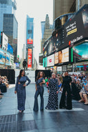 Four models in Sexy Day, Black Diamond, Supernova, and Fringy Baby walk the runway in Times Square, showcasing fashion against a lively city backdrop.
