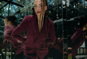 Stylish woman with long braids wearing a maroon blazer, posing against a mirrored background.