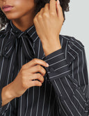 Close-up of a model's hands wearing a striped night top with a bow and cuffed sleeves, showcasing detailed fabric and design.