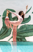 Model in Dancing Anyone outfit striking a pose by a pool with lush green foliage in the background.