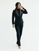 Woman in a stylish black suit showcasing comfort and elegance, featuring a tailored blazer and slim-cut pants.