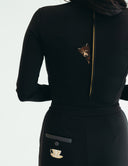 Back view of a sleek black suit showcasing a unique bear embroidery and a tea cup design on the pocket.