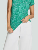 Woman wearing a green Signature Luxe Tee with white pants, showcasing its stylish design and comfortable fabric.