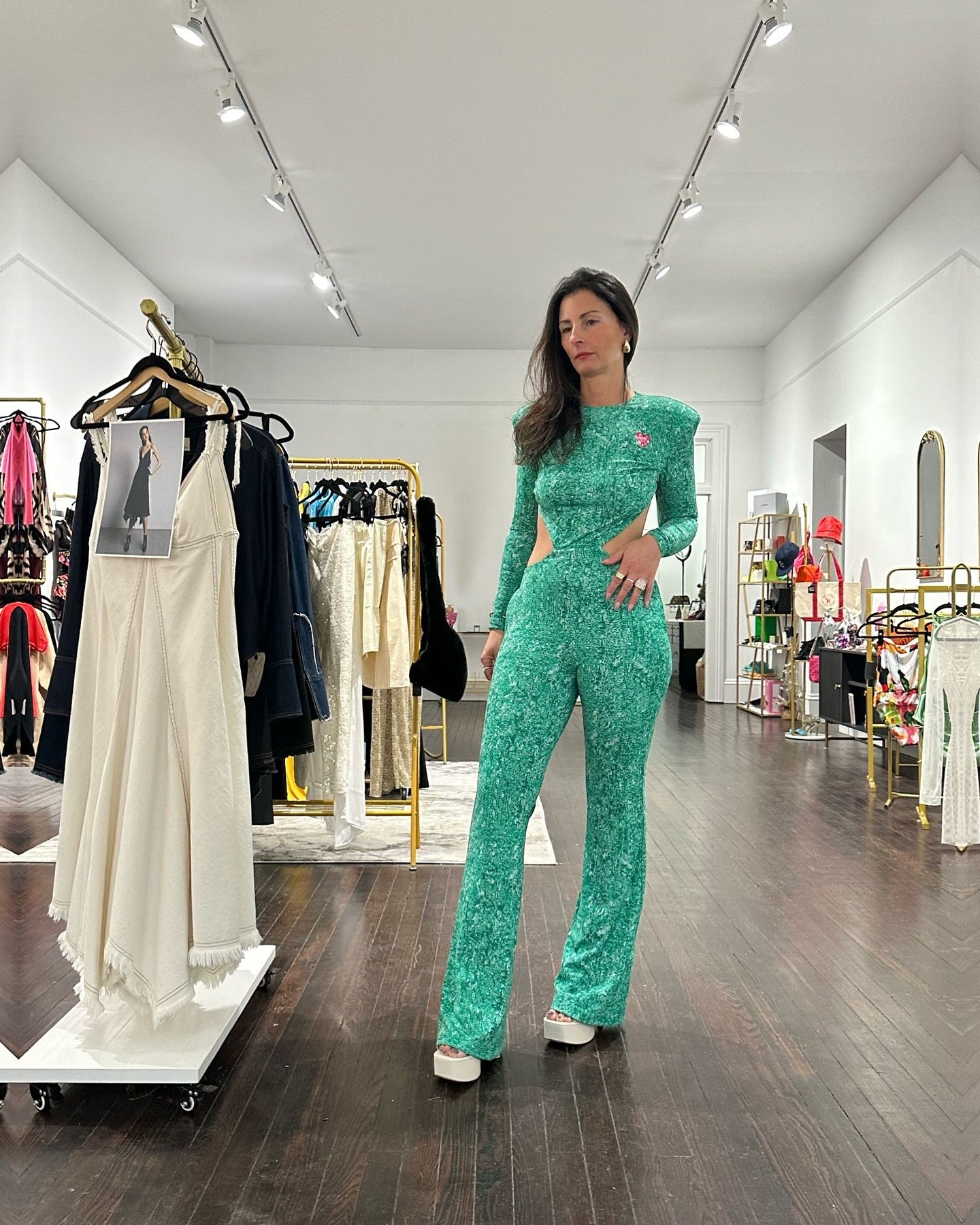 Woman in Verde Mi Amor poses stylishly in a boutique with vibrant clothing displays.