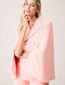 Cool Intentions Blazer worn by a model, showcasing its batwing sleeves and satin lapels in a soft pink color.