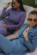 Two stylish women in fashionable outfits lounging outdoors, showcasing modern fashion trends and summer style.