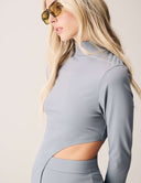 Woman modeling the Cut to the Chase Top in grey with a stylish cutout detail and sunglasses.