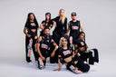 Diverse dance crew posing in stylish outfits, showcasing fashion and unity in a dynamic group setting.