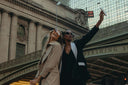 Two stylish women taking a selfie in front of Grand Central Terminal, showcasing urban fashion and joyful moments.