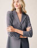 Close-up of a woman wearing the Keep It Moving Blazer with a grey hue, featuring a refined open back tuxedo silhouette.
