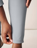 Detail of hands adjusting the hem of Keep It Moving Pant in light gray, showcasing its sleek design and high-performance fabric.