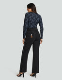 Model showcasing Luxe Long Sleeve Bodysuit in black lace with high-waisted black pants.