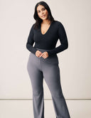 Model wearing Luxe Long Sleeve Bodysuit with scoop neckline and fitted gray pants.