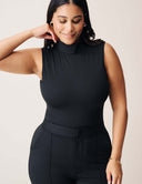 Model wearing the Luxe Sleeveless Bodysuit in black with sleek turtleneck design.