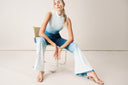 Model wearing a stylish ombre outfit with a fitted top and flared pants, seated gracefully on a chair.