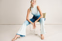 Woman in a stylish blue ombre jumpsuit seated on a chair, showcasing modern fashion and elegance.