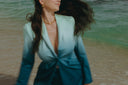 Woman in an ombre suit with flowing hair at the beach, showcasing a stylish coastal look.