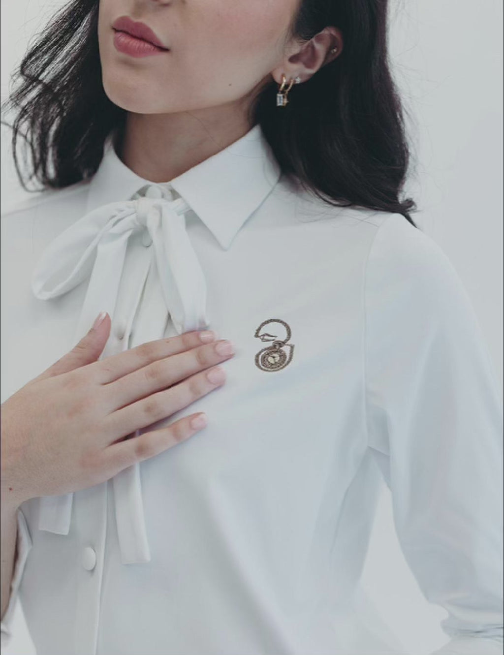 Elegant white buttoned blouse with neck bow, part of the Meet Me at Noon corporate suit collection.