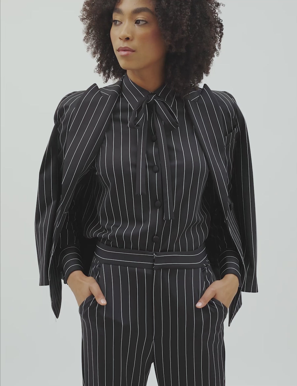 Model showcasing the Striped Night power suit with a double lined blazer and flared pants, perfect for any occasion.Model showcasing the Striped Night power suit with a double lined blazer and top, perfect for any occasion.