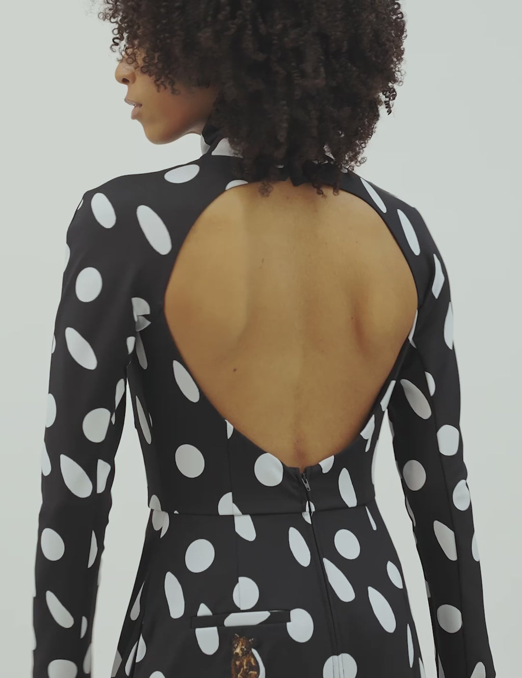 Close up of open back polka dotted dress with flowy skirt and pockets, perfect for sophisticated day wear.
