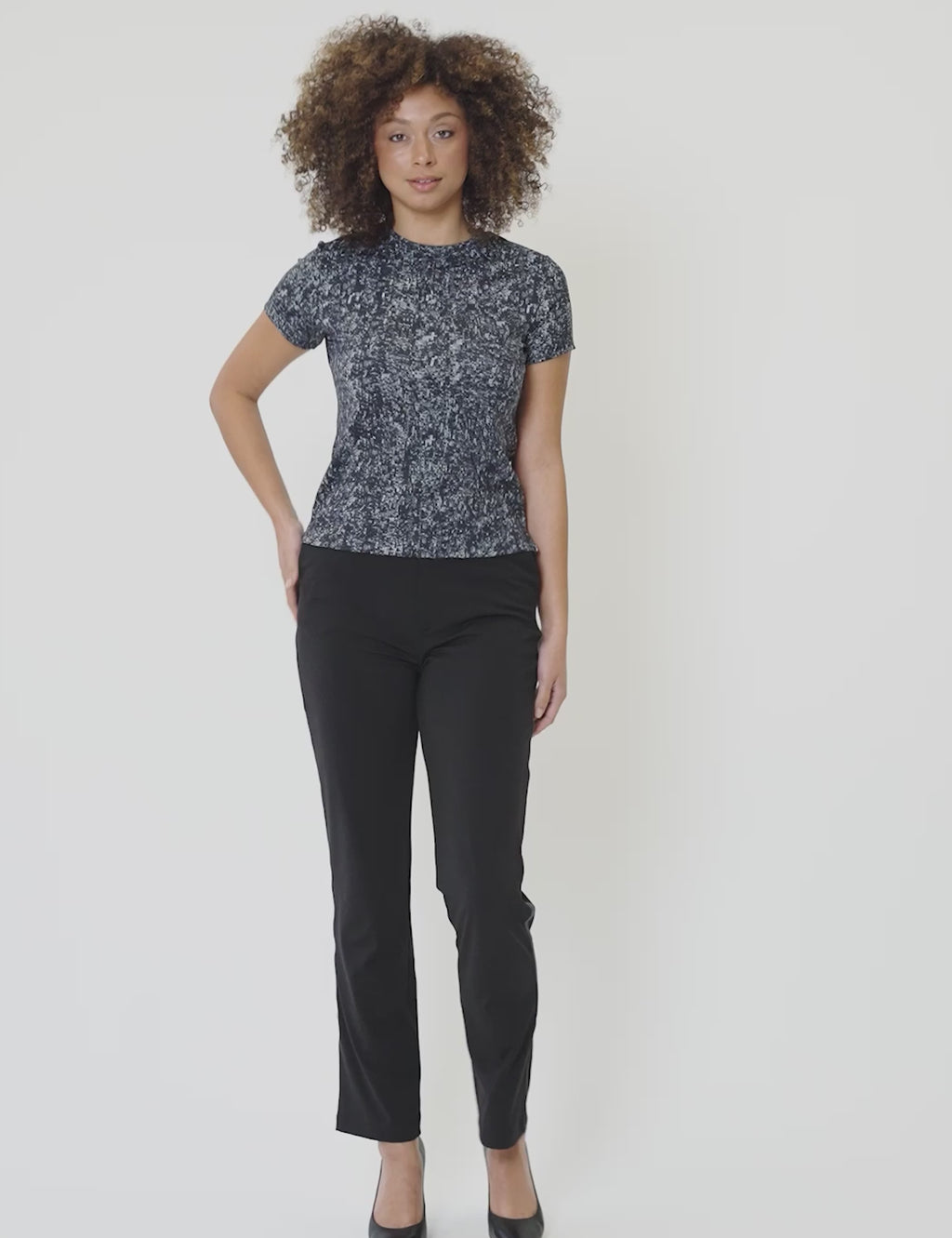 Model wearing Signature Luxe Tee in original lamé print paired with black pants, showcasing a stylish casual look.